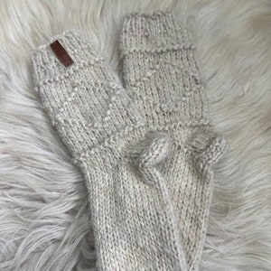 May include: A pair of beige knitted socks with a brown leather tag. The socks are made of a soft, warm material and have a simple, classic design.