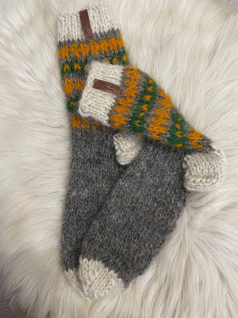 May include: Pair of grey, white, green and yellow wool socks with a brown leather tag that says "SOUVENIR".