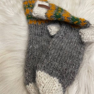 May include: A pair of grey, white and yellow striped knitted wool socks with a brown leather tag. The socks are folded over and the tag is visible.