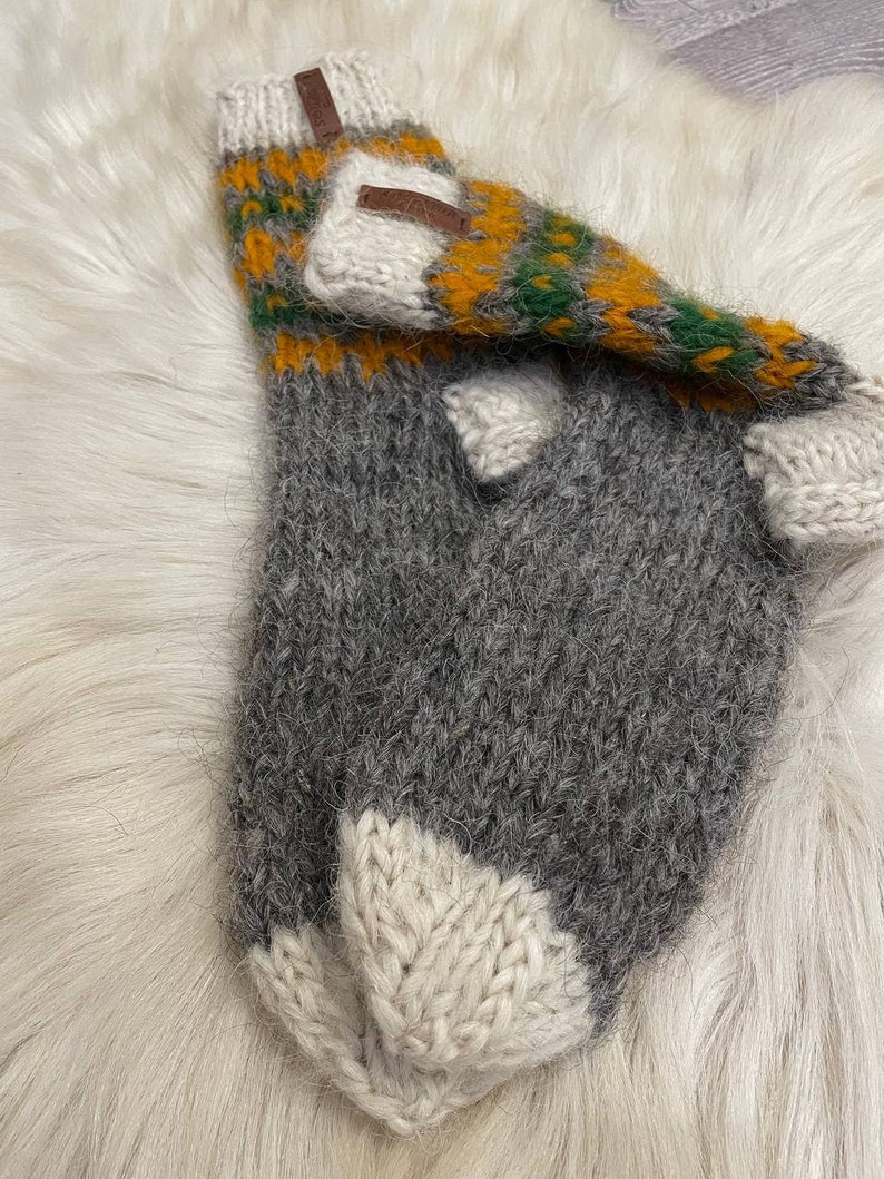 May include: A pair of grey, white and yellow striped knitted wool socks with a brown leather tag. The socks are folded over and the tag is visible.
