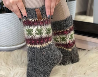 May include: Grey wool socks with a burgundy, green and white patterned cuff. The socks are thick and fluffy.