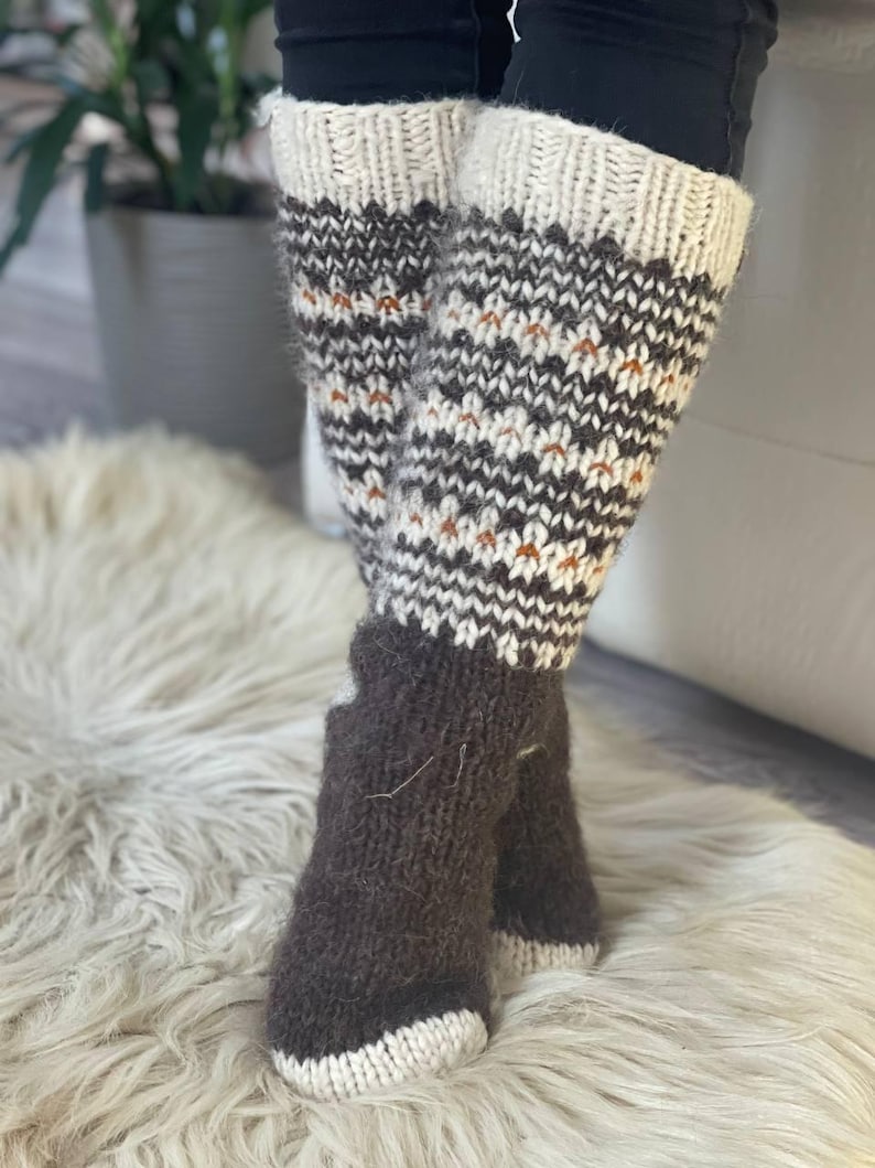 Puede incluir: Calentadores y calcetines de punto hechos a mano. Los calentadores tienen una parte superior e inferior de color crema con un patr&oacute;n geom&eacute;trico en marr&oacute;n y blanco. Los calcetines son de color marr&oacute;n liso con una puntera color crema. Los calentadores miden unos 30 cm de largo.