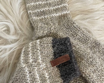 May include: Pair of brown and white striped wool socks with a brown leather tag that says "Souvenir Iceland".