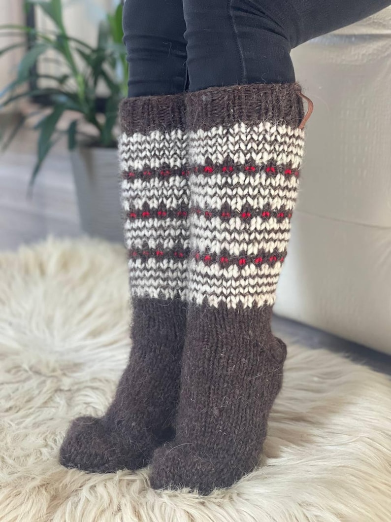 May include: Knee-high wool socks in brown, white, and red. The socks have a patterned design on the upper portion and a solid brown foot. The socks are thick and appear warm, suitable for cold weather.
