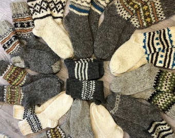 May include: A selection of hand-knitted wool socks in various colours and patterns. The socks feature designs in grey, white, brown, and blue. The socks are arranged in a circular pattern, showcasing their unique textures and styles.