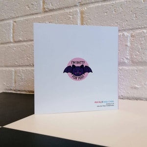 May include: A pink and white greeting card with a black bat illustration and the text "I'm Batty For You".