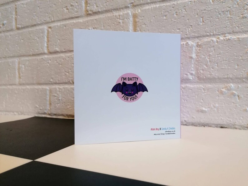 May include: A pink and white greeting card with a black bat illustration and the text "I'm Batty For You".