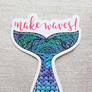 Może przedstawiać: Naklejka w kształcie ogona syreny, z szczeg&oacute;łowym wzorem w odcieniach niebieskiego, turkusowego i fioletowego. Fraza "make waves!" jest napisana r&oacute;żowym pismem u g&oacute;ry. Naklejka ma białą obw&oacute;dkę.