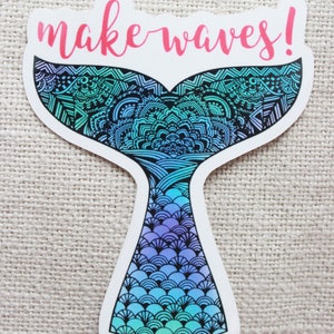 Może przedstawiać: Naklejka z motywem ogona syreny. Ogon ma gradient niebieskiego, turkusowego i fioletowego z misternymi czarnymi wzorami. R&oacute;żowy napis nad nim to "make waves!"