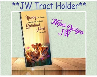 Puede incluir: Un portafolletos con espiral con el texto "Felices los que son conscientes de su necesidad espiritual" y "Mateo 5:3". La portada presenta una ilustración de tres cachorros de león. También se ven las palabras "JW Tract Holder" y "Hopes Designs JW".