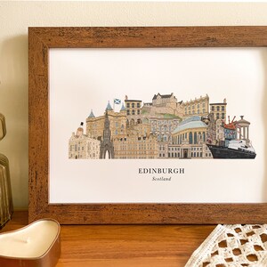 May include: A framed print of a colorful illustration of the Edinburgh skyline, featuring iconic landmarks like Edinburgh Castle and the Scottish Parliament. The print is titled "EDINBURGH, Scotland".