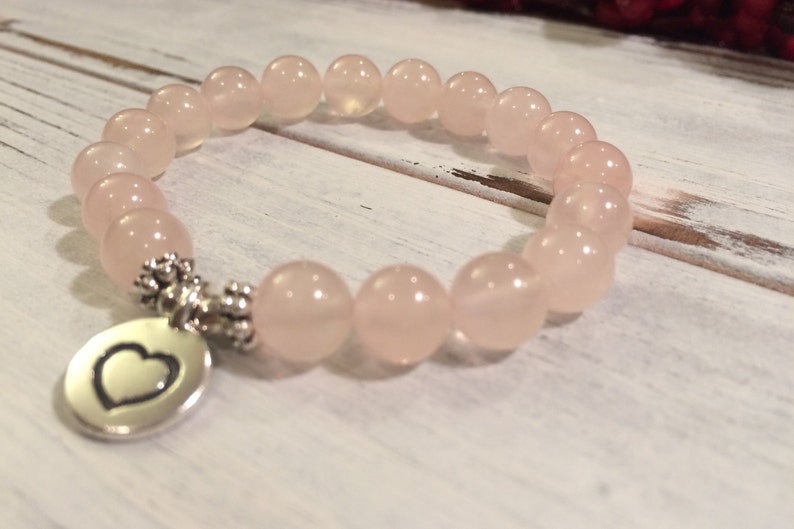 May include: A pink rose quartz beaded bracelet with a silver heart charm. The bracelet is made with 8mm beads and is approximately 7 inches in length.