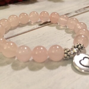 May include: A pink rose quartz bracelet with a silver heart charm. The bracelet is made of 8mm beads and is stretchy.