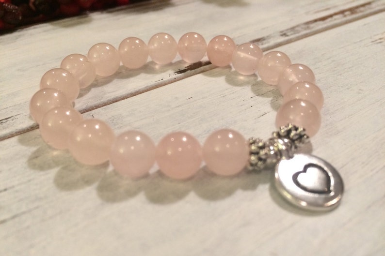 May include: A pink rose quartz bracelet with a silver heart charm. The bracelet is made of 8mm beads and is stretchy.