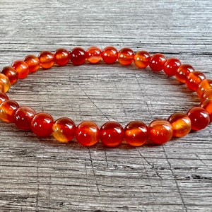 Peut inclure: Un bracelet en pierre de cornaline avec des perles orange-rouge.