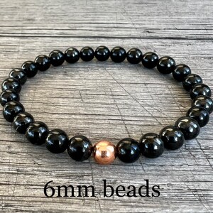 May include: Black beaded bracelet with a single copper bead accent. 6mm beads.