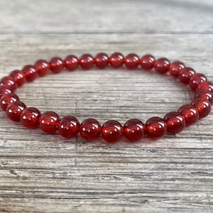May include: A red carnelian gemstone bracelet with round beads.