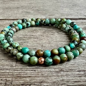 May include: A double-strand bracelet made of green and brown turquoise beads with a copper accent bead.