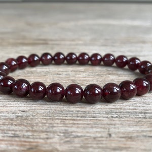 Peut inclure: Un bracelet en pierres précieuses rouges composé de perles rondes. Le bracelet est fait de pierres naturelles et est un choix populaire pour les bijoux.
