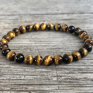 May include: A brown and gold beaded bracelet made of tiger's eye stones.