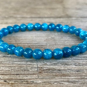 May include: A blue gemstone bracelet with round beads. The bracelet is made of natural stones and is a beautiful shade of blue.