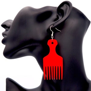 May include: Red comb-shaped earrings. The earrings are made of wood and have a shiny finish.