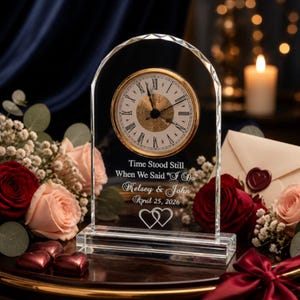 May include: An arched clear glass clock featuring a gold-rimmed face with Roman numerals. The glass is engraved with the text: Time Stood Still When We Said "I Do", Kelsey & John, April 25, 2026, and two interlocking heart outlines.
