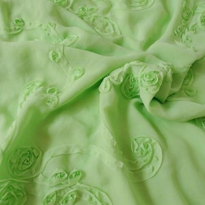 Peut inclure: Tissu vert clair avec un motif floral 3D. Le tissu est doux et fluide, et les fleurs sont d&eacute;licates et complexes.