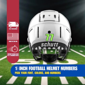 Puede incluir: Un casco de fútbol americano blanco con una máscara facial negra y el número 77 verde en la parte posterior. El casco tiene un logotipo negro "schutt" en la parte posterior. Números de casco de fútbol de 1 1/2 pulgadas.