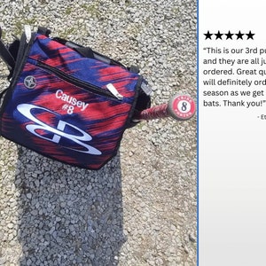 Pode incluir: Uma bolsa de beisebol vermelha, branca e azul com o nome "Causey #8" impresso nela. A bolsa est&aacute; sobre uma superf&iacute;cie de cascalho ao lado de um taco de beisebol com um adesivo vermelho e branco que diz "Tribe #8"