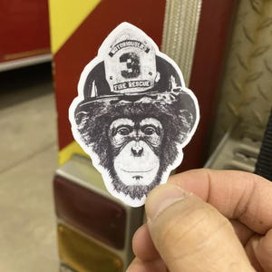 May include: Black and white sticker of a chimpanzee wearing a firefighter helmet with the text "NOTORIOUSLB3 FIRE RESCUE" on it.