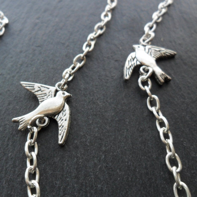 May include: Silver chain necklace with three silver dove charms. The doves are in flight position with their wings spread.