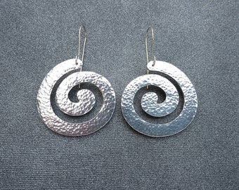 May include: A pair of silver earrings with a hammered finish and a spiral design.