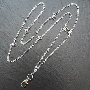 May include: Silver chain with a lobster clasp and multiple monkey charms. The chain is approximately 76 cm long.