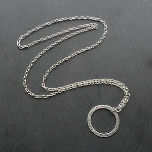 Puede incluir: Collar de cadena de plata con un colgante circular que tiene las palabras "Dream Love Trust Hope" grabadas a su alrededor.