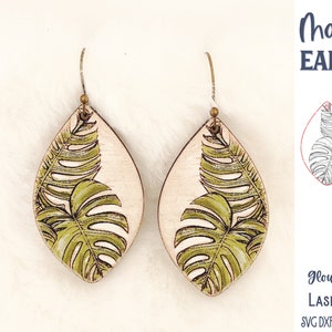 May include: Teardrop-shaped wooden earrings featuring a green and black monstera leaf illustration. The text reads Monstera Earrings, Glowforge Tested Laser Cut File, SVG DXF PNG JPG EPS PDF AI, and Wispy Willow Designs.