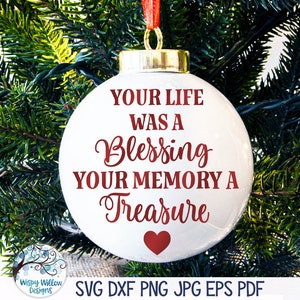 May include: White Christmas ornament with red text that reads "Your life was a blessing your memory a treasure". A red heart is at the bottom of the ornament.