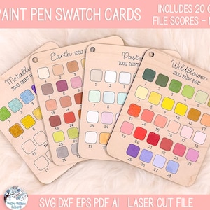 May include: Four light-colored wooden swatch cards labeled Tooli Paint Pen Swatch Cards, featuring color-coded grids for Metallic, Earth, Pastel, and Wildflower sets. Each card includes numbered squares for paint samples and a hole for hanging.