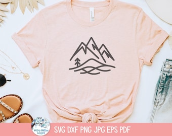 May include: A pink t-shirt with a black line drawing of mountains and a tree on the front. The shirt is laid flat on a white surface with other accessories around it.