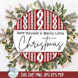 May include: A circular sign featuring a red and white cable knit sweater pattern on the top and bottom sections, with a white center band displaying the black text Have Yourself A Merry Little Christmas in a mix of serif and script fonts.