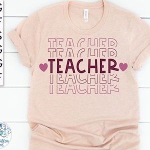 May include: A light pink t-shirt with the word "TEACHER" printed in a retro style with hearts on either side. The word "TEACHER" is repeated in a smaller font size above and below the main word.