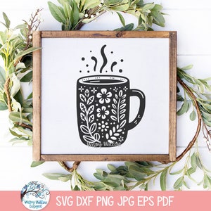 May include: A black and white illustration of a coffee mug with a floral design and steam rising from the top. The mug is on a white background.