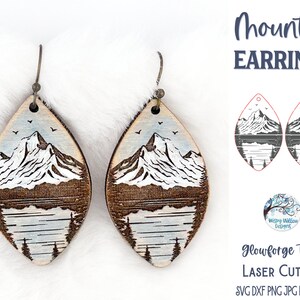 May include: A pair of wooden mountain earrings with a light blue and brown design. The earrings are shaped like a teardrop and feature a mountain scene with a lake and trees. The text "Mountain Earrings" is written in blue at the top of the image. The text "Glowforge Tested Laser Cut File SVG DXF PNG JPG EPS PDF AI" is written in black at the bottom of the image.