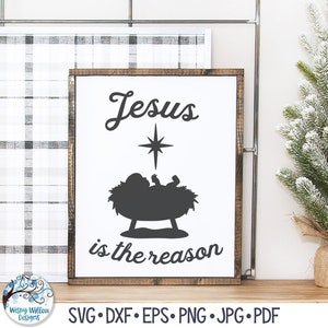 May include: A rectangular wooden sign with a white background and a dark brown frame. The sign features a black silhouette of a baby in a manger beneath a star, with the black text Jesus is the reason printed above and below the graphic.