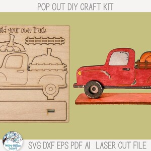 May include: A pop out DIY craft kit featuring a wooden sheet with laser-cut outlines for a truck, pumpkin, and fence, labeled Build your own Truck. Beside it is an assembled, painted red truck model carrying an orange pumpkin in the bed.
