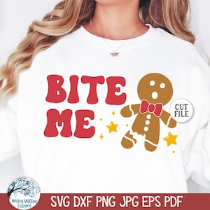 Puede incluir: Una sudadera blanca con el texto "Bite Me" en letras rojas y un hombre de jengibre con una pajarita roja. El hombre de jengibre le falta un trozo de pierna y tiene una expresión de sorpresa en su rostro. Hay estrellas doradas alrededor del hombre de jengibre.