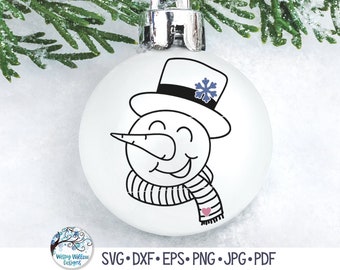 May include: A white spherical Christmas ornament featuring a black line art illustration of a snowman wearing a top hat with a blue snowflake accent and a striped scarf with a small pink heart. The ornament has a silver metal cap at the top.