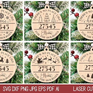 Op de afbeelding: Zes ronde houten ornamenten met een zwart-wit geruit lint. Elk ornament heeft de tekst "There's no place like home" en een nummer, "27545". De ornamenten hebben verschillende ontwerpen, waaronder sneeuwvlokken, een huis, een rendier, een slee en kerstboom.