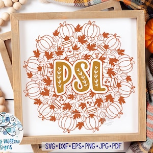 Op de afbeelding: Een ingelijst bord met een herfstthema. Het kunstwerk toont pompoenen, koffiekopjes en bladeren in tinten oranje en bruin, gerangschikt rond de letters "PSL". Het bord zit in een houten frame.