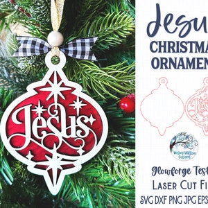 May include: A laser-cut Christmas ornament featuring the word Jesus in a stylized font, layered with a white frame over a red background. It includes a black and white buffalo check ribbon, a wooden bead, and a gold hanging cord.